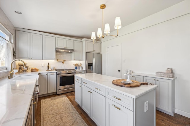 kitchen featuring dark wood finished floors, decorative backsplash, appliances with stainless steel finishes, and a sink