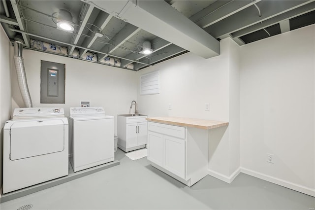 laundry area with baseboards, electric panel, cabinet space, washer and dryer, and a sink