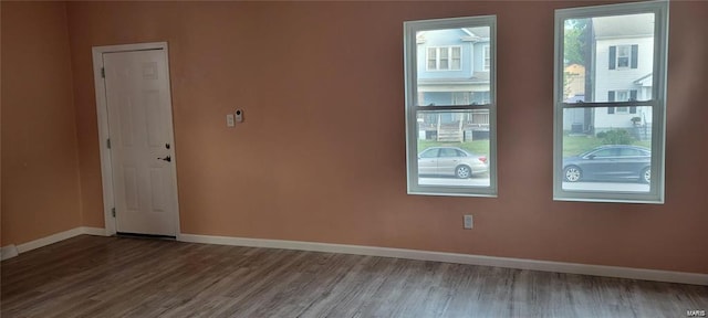 spare room with baseboards and wood finished floors