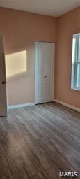 unfurnished bedroom with a closet, wood finished floors, and baseboards