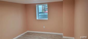 spare room with baseboards and wood finished floors