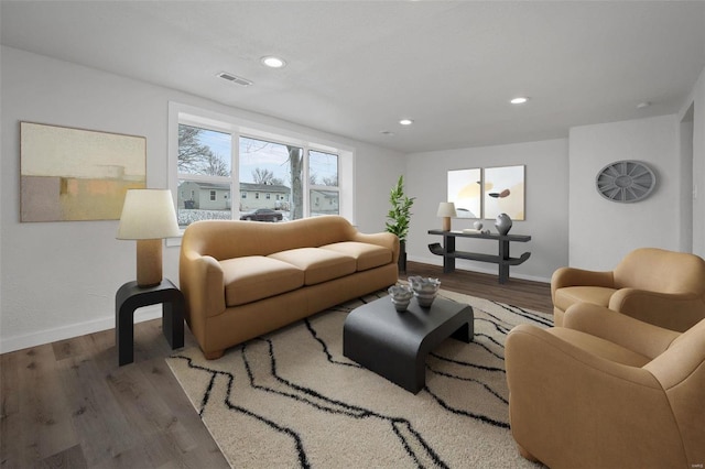 living area featuring baseboards, visible vents, and wood finished floors