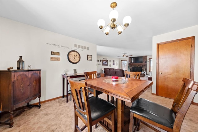 dining area featuring baseboards, visible vents, light carpet, a brick fireplace, and ceiling fan with notable chandelier