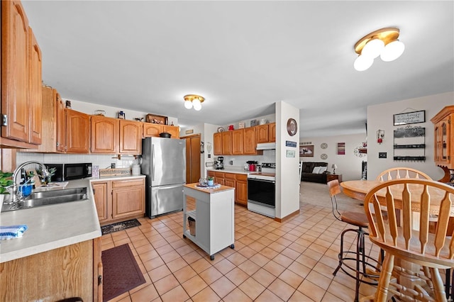 kitchen with black microwave, under cabinet range hood, freestanding refrigerator, electric stove, and a sink