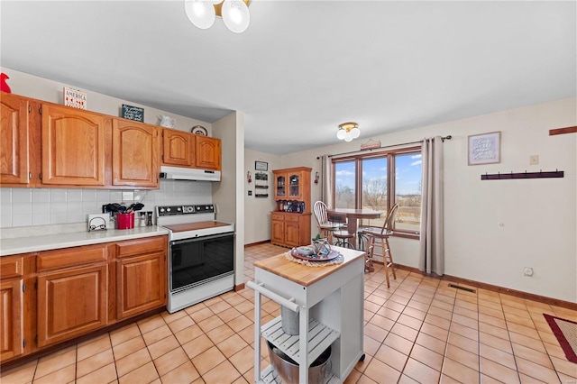 kitchen featuring electric range, visible vents, under cabinet range hood, backsplash, and light countertops