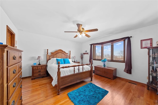 bedroom featuring light wood finished floors, visible vents, a ceiling fan, and baseboards