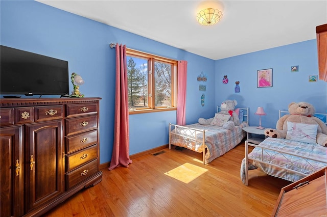 bedroom with visible vents, light wood-type flooring, and baseboards