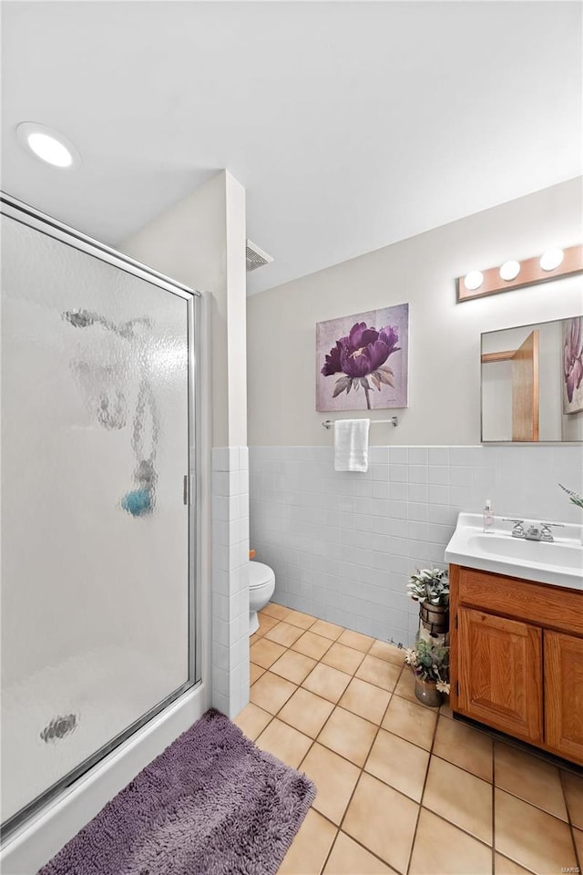 full bath featuring tile patterned floors, toilet, tile walls, a shower stall, and vanity