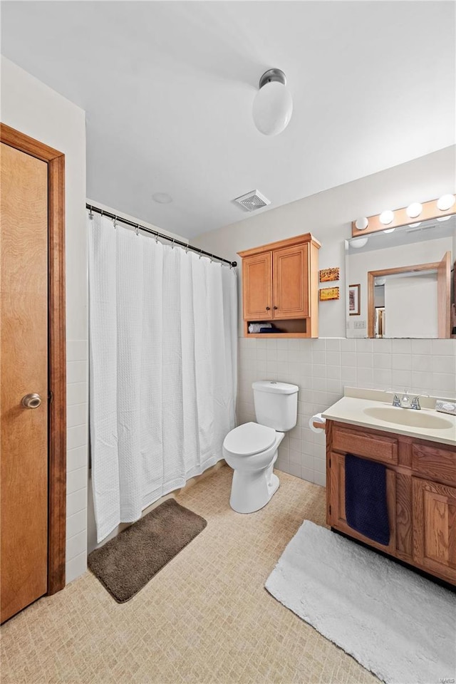 bathroom featuring vanity, a shower with shower curtain, visible vents, tile walls, and toilet