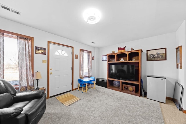 living area featuring light carpet, visible vents, and baseboards