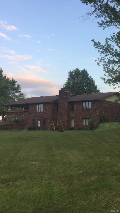 back of property with a yard and brick siding