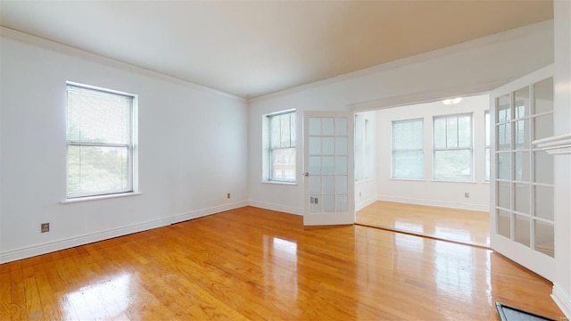 unfurnished room featuring a wealth of natural light, baseboards, and wood finished floors