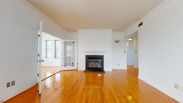 unfurnished living room with baseboards, a glass covered fireplace, ornamental molding, and light wood finished floors