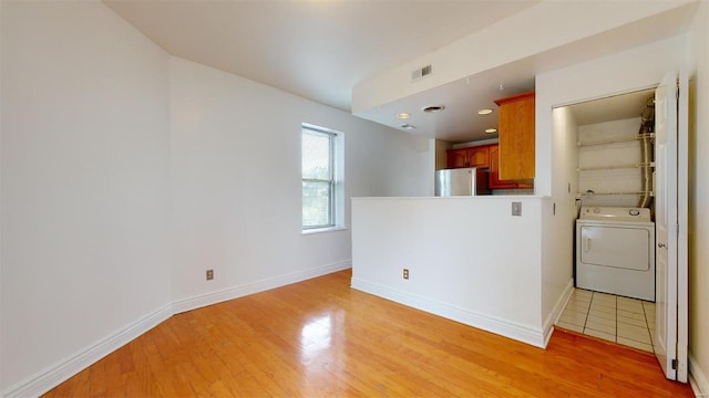 unfurnished room with light wood finished floors, visible vents, washer / clothes dryer, and baseboards