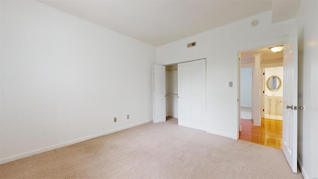 unfurnished bedroom featuring light carpet, visible vents, baseboards, and a closet