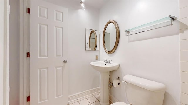 bathroom with tile patterned flooring, toilet, baseboards, and a sink