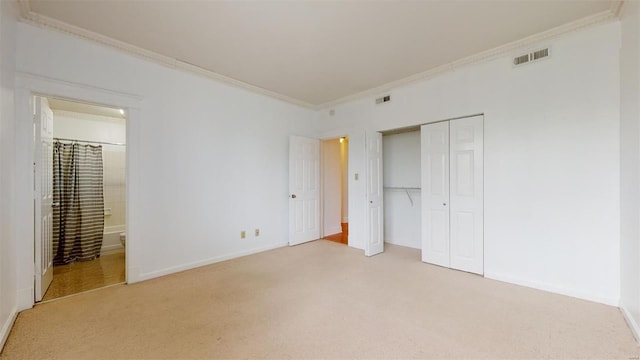 unfurnished bedroom featuring baseboards, visible vents, carpet floors, ornamental molding, and a closet