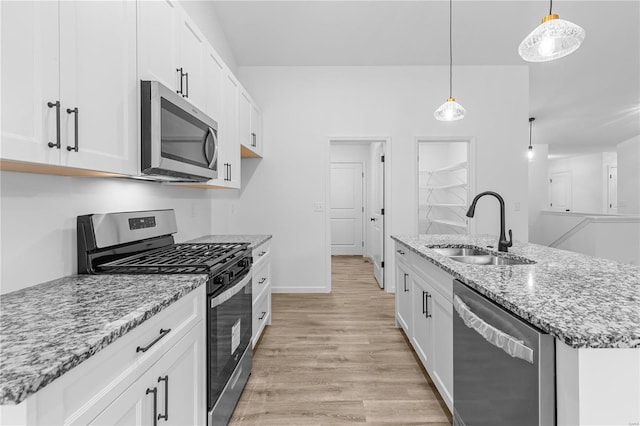 kitchen featuring a sink, white cabinetry, appliances with stainless steel finishes, light wood finished floors, and an island with sink