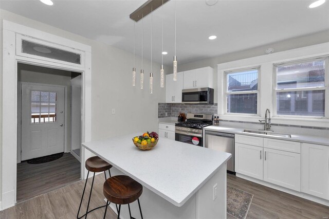 kitchen with backsplash, wood finished floors, appliances with stainless steel finishes, and a sink