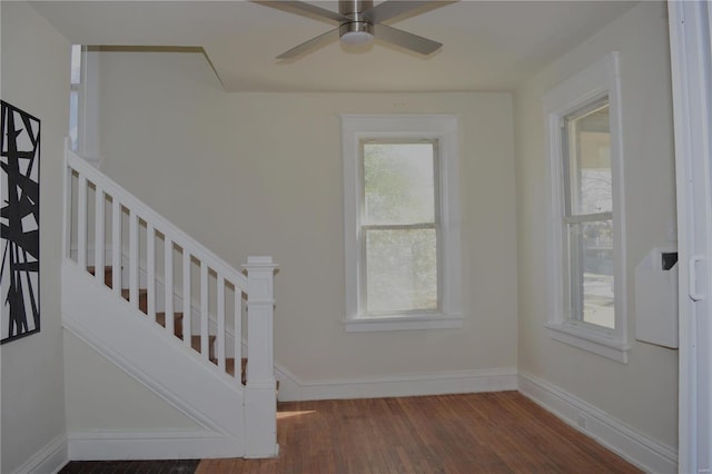 stairs featuring wood finished floors, baseboards, and ceiling fan