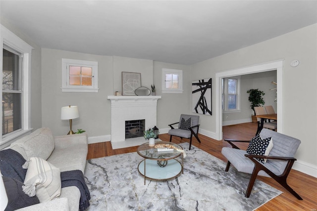 living area with a brick fireplace, baseboards, and wood finished floors