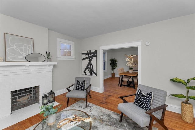 living area with baseboards, wood finished floors, and a fireplace