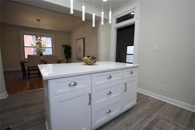 kitchen with baseboards, dark wood finished floors, light countertops, white cabinetry, and decorative light fixtures