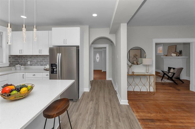 kitchen featuring light wood-type flooring, a kitchen bar, stainless steel fridge, and tasteful backsplash