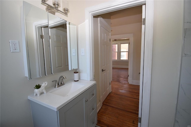 bathroom with baseboards, wood finished floors, and vanity