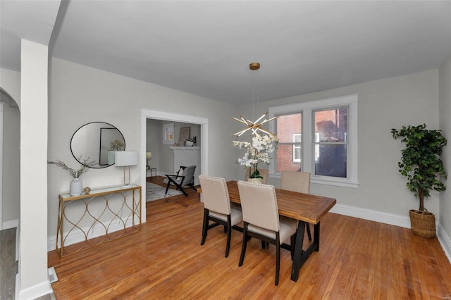 dining room with arched walkways, baseboards, and wood finished floors