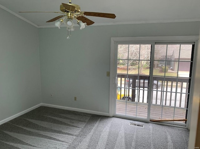 carpeted empty room featuring ceiling fan, ornamental molding, visible vents, and baseboards