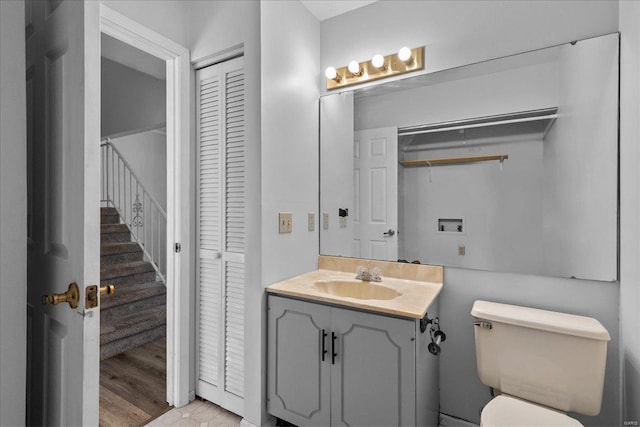 bathroom with toilet, a closet, and vanity