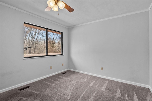 carpeted empty room with a ceiling fan, visible vents, crown molding, and baseboards