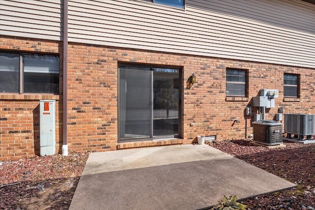 property entrance with brick siding, a patio area, and cooling unit