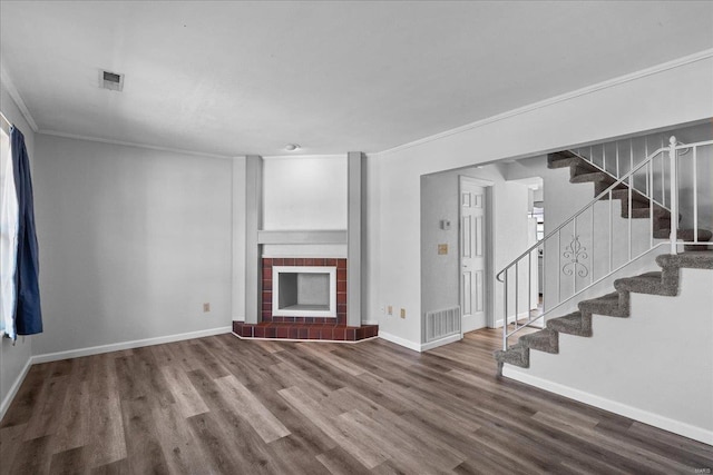 unfurnished living room with stairway, a fireplace, visible vents, and wood finished floors