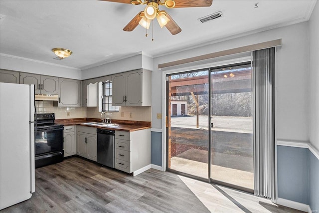 kitchen featuring under cabinet range hood, black range with electric stovetop, stainless steel dishwasher, gray cabinets, and freestanding refrigerator