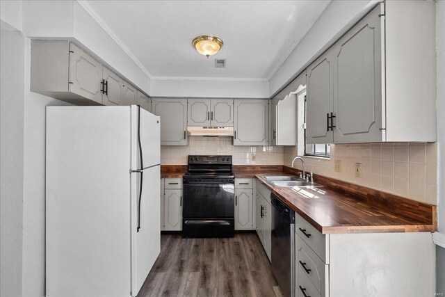 kitchen featuring dishwashing machine, under cabinet range hood, butcher block counters, freestanding refrigerator, and black electric range oven