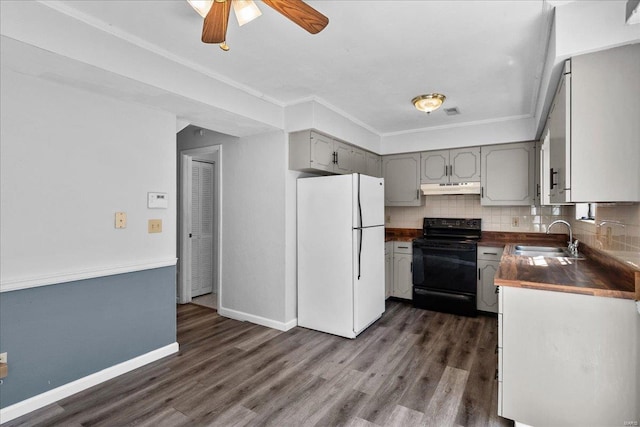 kitchen with dark countertops, freestanding refrigerator, black / electric stove, under cabinet range hood, and a sink