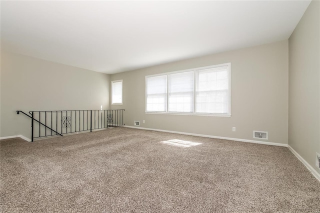 carpeted spare room with visible vents and baseboards