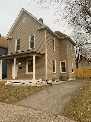 rear view of property with covered porch, a chimney, fence, and central air condition unit