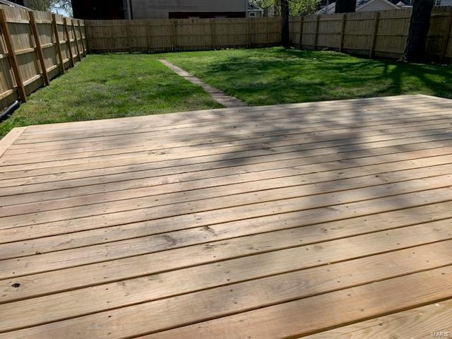 deck with a fenced backyard and a lawn
