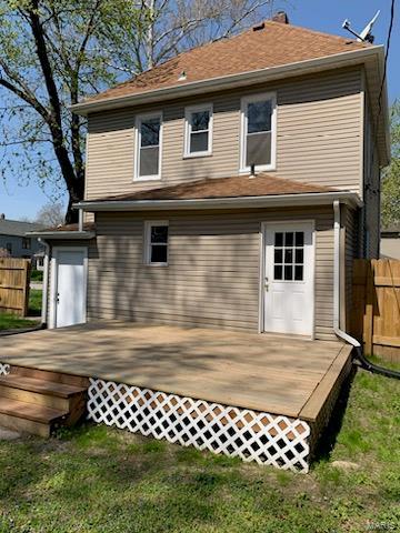 rear view of property with a deck, fence, and a lawn