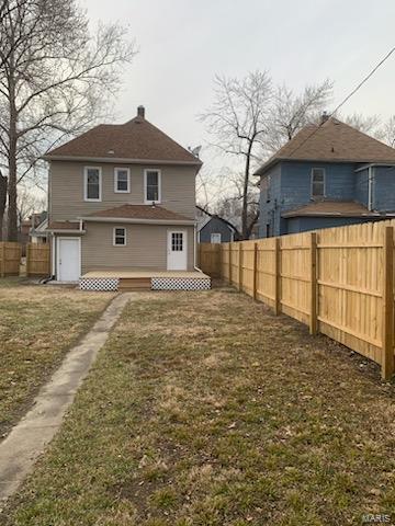 rear view of house featuring a lawn and fence private yard