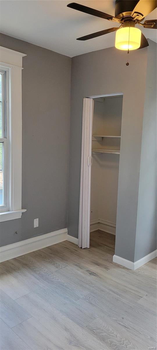 unfurnished bedroom with a closet, light wood finished floors, and multiple windows