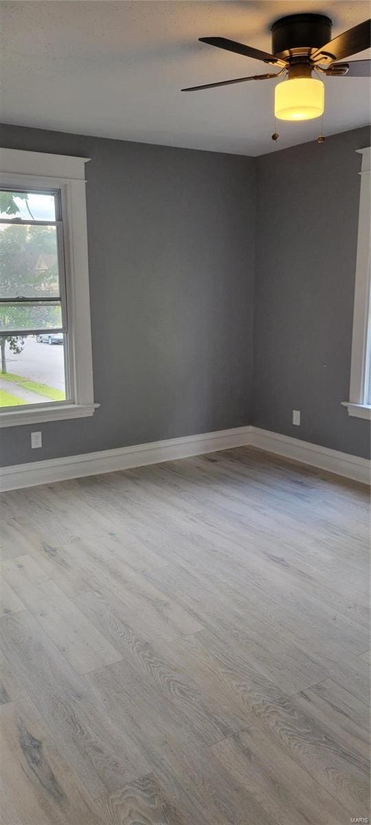 spare room with wood finished floors, ceiling fan, and baseboards