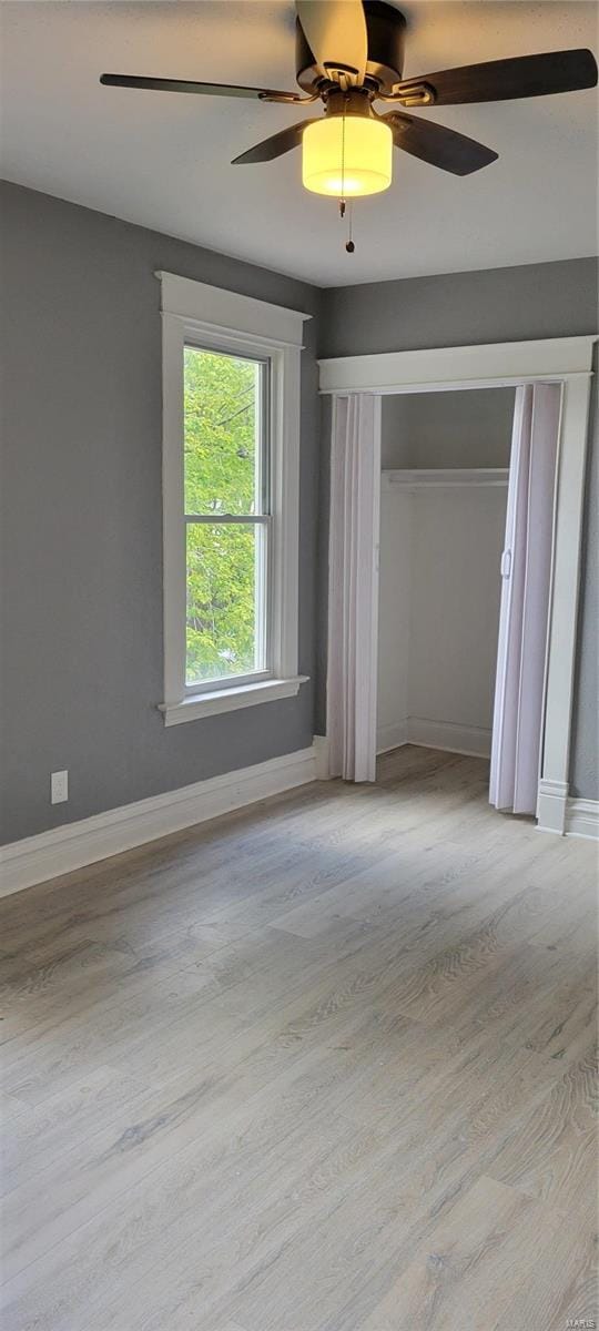 unfurnished bedroom featuring a closet, baseboards, ceiling fan, and wood finished floors