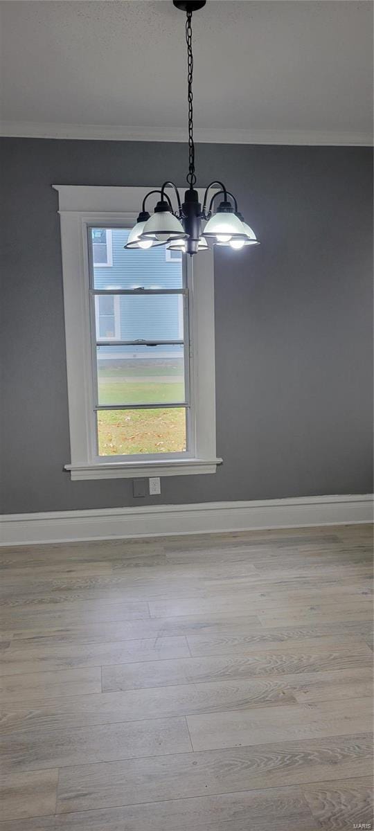 room details featuring crown molding, wood finished floors, an inviting chandelier, and baseboards