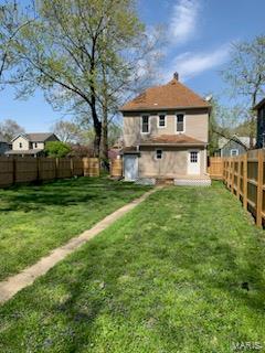 rear view of property featuring a yard and a fenced backyard