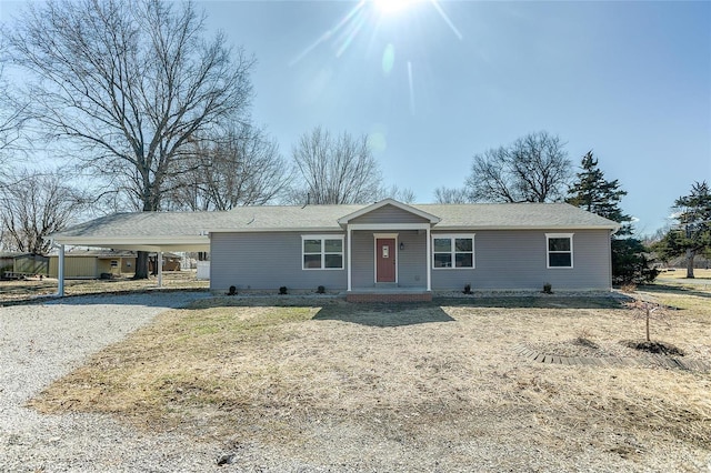 ranch-style house featuring an attached carport and gravel driveway