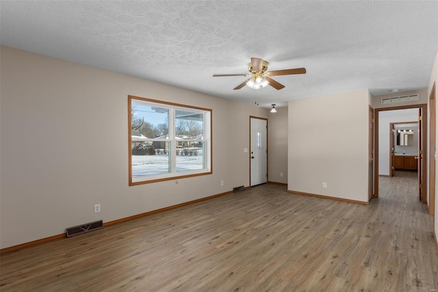 empty room featuring light wood finished floors, baseboards, and visible vents